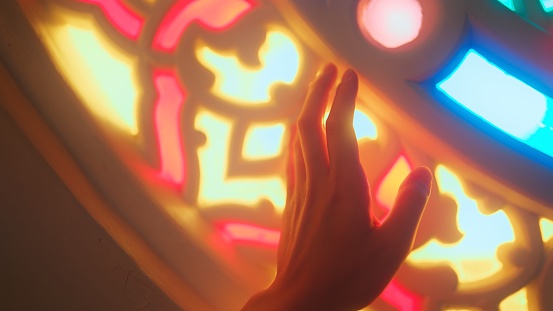 A close-up video of young female tourist's hand touching stained glasses in a mosque.