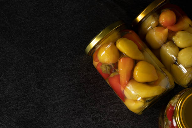Pickled mini peppers in a jar isolated on dark background with copy space stock photo