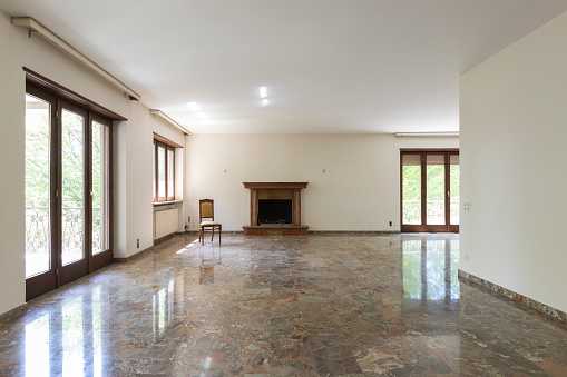 Large living room with white walls and marble floor. Interior vintage abandoned villa ready to be demolished
