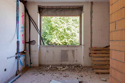 Large bright room with windows of an ancient villa undergoing renovation. The old walls have been torn down and new ones have been created. Nobody inside