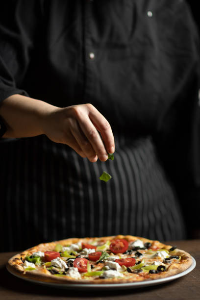 레스토랑의 여성 요리사가 피자 마르게리타를 장식합니다. - chef cooking pasta professional occupation 뉴스 사진 이미지