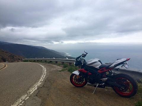 Triumph Street Triple RX motorcycle, stopped on the side of a road and in the background the sea, Malibu, California, USA. October 2016.