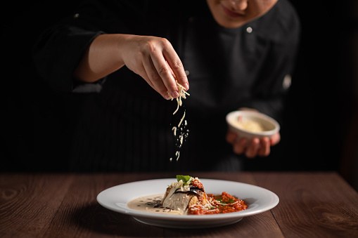 Closeup of female chef in restaurant decorates the meal.