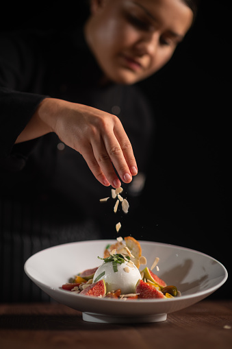 Closeup of female chef in restaurant decorates the meal.