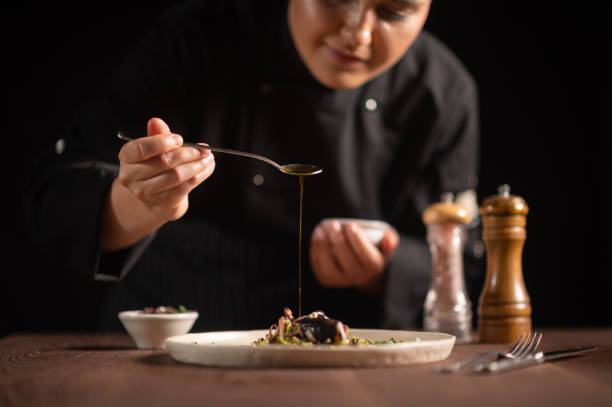 Female chef pouring sauce on meal stock photo