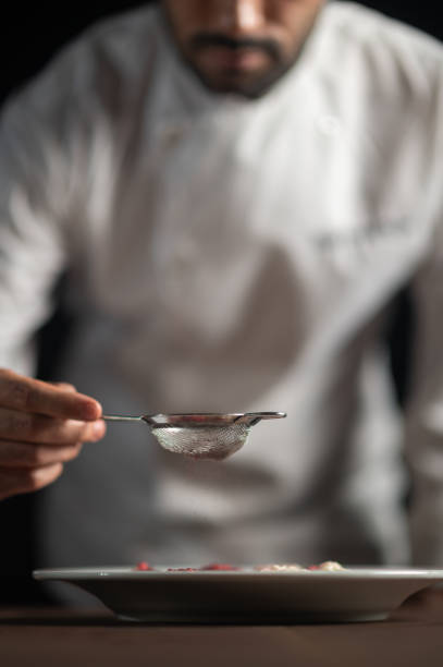 Closeup of hand of male chef in restaurant decorates the meal stock photo