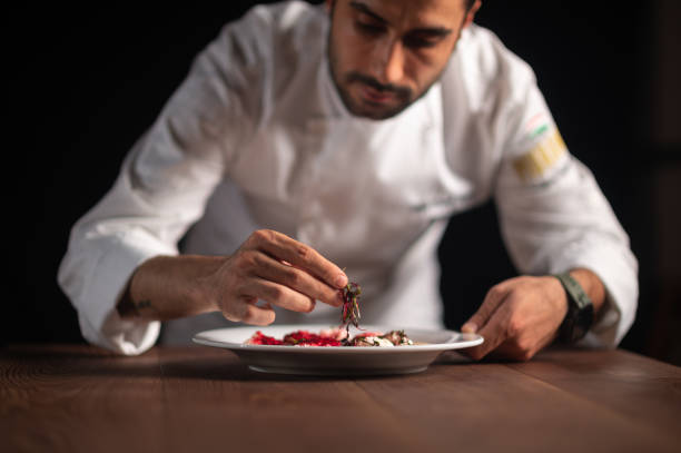 Closeup of male chef in restaurant decorates the meal stock photo