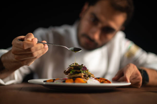 A male chef pouring sauce on meal stock photo