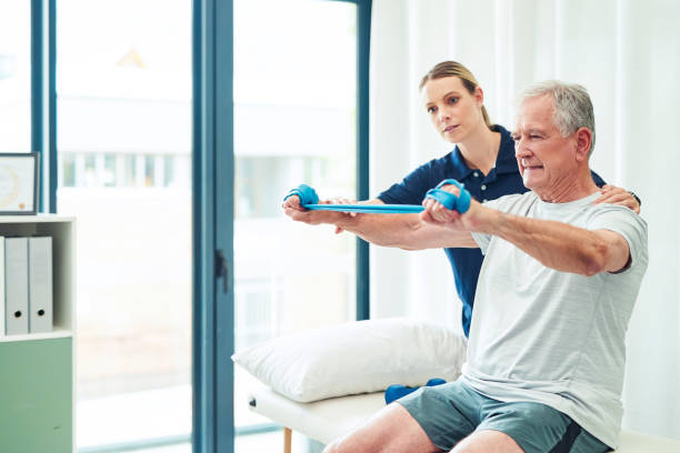 Physiotherapy doctor, senior patient and band for stretching, physical therapy and orthopedic health. Physiotherapist, chiropractor and nurse help elderly man, osteoporosis and surgery rehabilitation stock photo