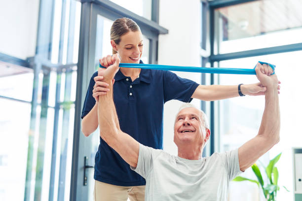 istock Physiotherapy, senior man and arm band exercise for physical therapy, motion workout and movement training. Help, rehabilitation and recovery support for elderly person  from expert healthcare worker 1428417067