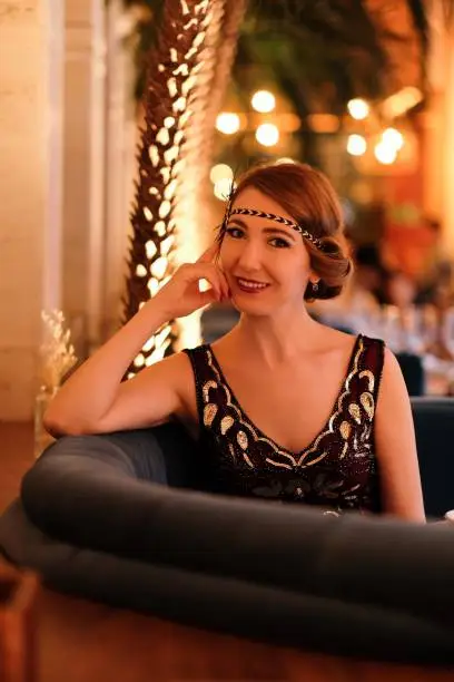 Woman in 1920 style clothes with a glass. Beautiful girl retro flapper style retro vintage roaring 20s.