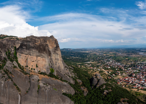 Meteora Greece at sunrise, Blue sky with clouds over Monastery buildings on top of rocks and Kalambaka town and valley. Europe travel destination