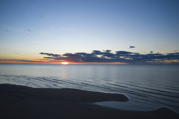 vista dalla spiaggia all'acqua del mare, onde con schiuma bianca, pierce e cielo con nuvole in una bella serata - imbrunire foto e immagini stock