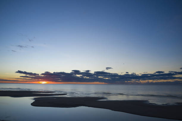 scena del tramonto paesaggistico sulla costa occidentale dell'irlanda con l'ultima luce che brilla attraverso le nuvole temporalesche riflesse nel mare durante il tempo tempestoso in estate nella contea di kerry. - tramonto foto e immagini stock