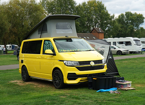 St Neots, Cambridgeshire, England - September 20, 2022: Modern Yellow Volkswagen Camper  Van with high top up and awning on campsite.