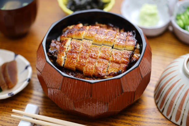 Hitsumabushi is a Japanese Nagoya rice dish decorated with grilled Unagi eel at the top. The eel is served in smaller pieces that allows it to be enjoyed with simply plain rice, or accompanying condiments and an original soup stock or hot tea. hitsumabushi es un plato de arroz japonés de nagoya decorado con anguila unagi a la parrilla en la parte superior. la anguila se sirve en trozos más pequeños que permiten disfrutarla simplemente con arroz simple, o acompañando condimentos y un original