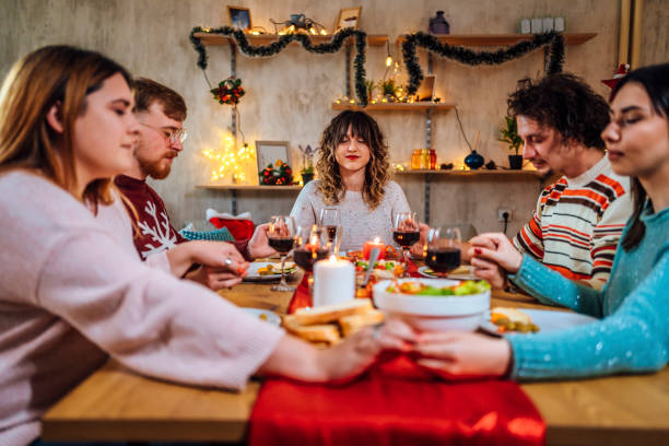 istock Friends holding hands in prayer before dinner 1428426449