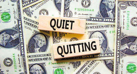 Quiet quitting symbol. Concept words Quiet quitting on wooden blocks. Beautiful background from dollar bills. Business and quiet quitting concept. Copy space.