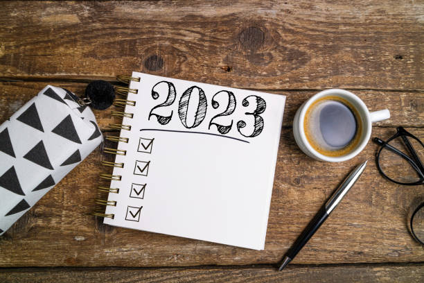 istock New year goals 2023 on desk. 2023 resolutions list with notebook, coffee cup and eyeglasses on wooden background. Goals, plan, strategy, business, idea, action 1428432381