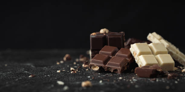 istock White, Milk and Dark square chocolate bars crushed with nuts on the black background 1428446807
