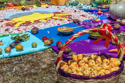 Tubers of oca - oxalis tuberosa - root vegetable in decorated basket as details of Andean cross or Chakana, Ceremony in homage to Pachamama (Mother Earth). Ritual of indigenous peoples of Andes.