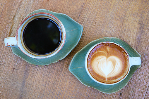 Top view of black coffee and hot cappuccino on wooden table