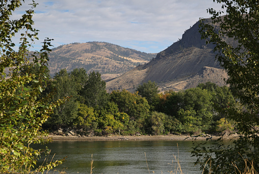 View from Riverside Park across the South Thompson River to the scenic hills of the Kamloops Indian Reserve No. 1. \nAutumn morning with light forest smoke and clouds in the Thompson-Nicola Regional District.