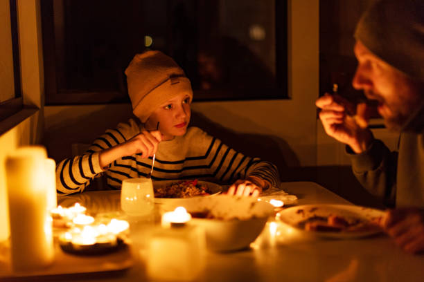 Family eating with candles during blackout Family eating with candles during blackout candle light dinner stock pictures, royalty-free photos & images