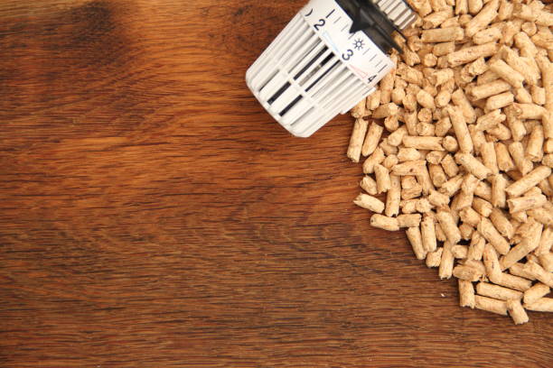 an old oak board with wood pellets and a radiator thermostat stock photo