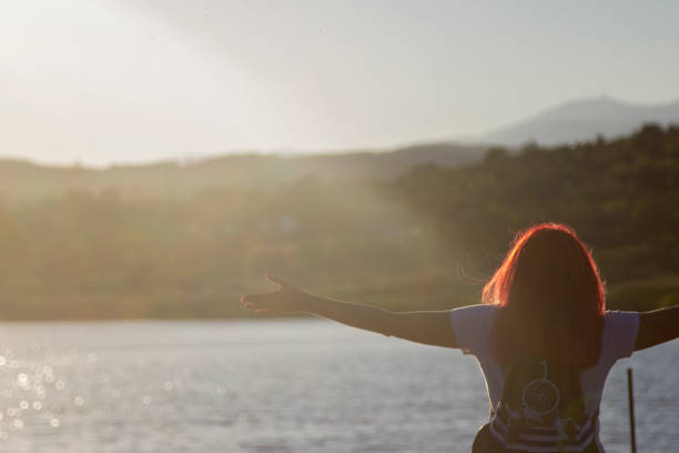 istock Young woman with outstretched hands at sunset 1428456050