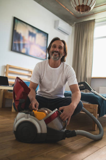 istock Man sitting on the floor and gathering the vacuum cleaner 1428463179
