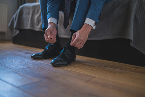 Putting on shoes. Man in blue suit putting on his shoes wile sitting on the sofa