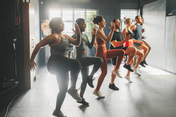 Diversity in gym class doing workout, training and exercise. Multicultural, happy and diverse people with different body shape and size exercising and active at a gym for fitness, wellness and cardio stock photo