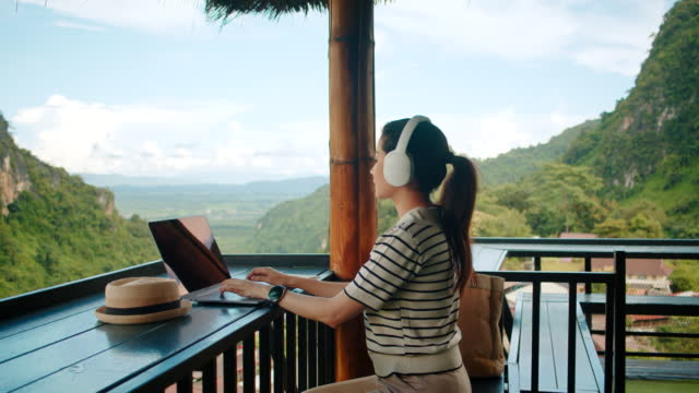 Freelance Digital nomad SEO SPECIALIST with wireless headphone Working remotely on laptop computer.