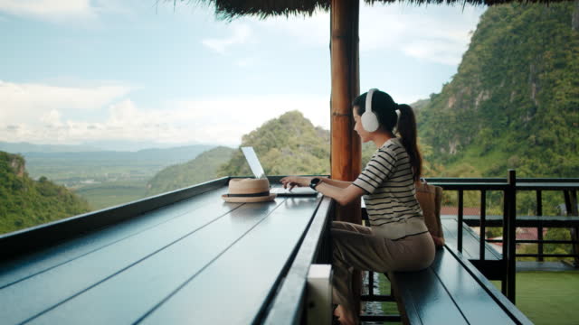 Mujer estudiante adulta que estudia la clase en línea en una computadora portátil en una cafetería al aire libre en la montaña. Moda sostenible con bolsos photo