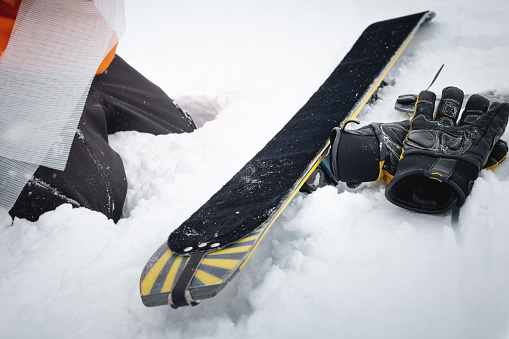 The skier stopped to put skins on skis. Gloves lie on the snow next to the ski. Trekking equipment for winter hiking.