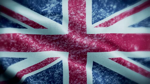 4K blizzard / snow over United Kingdom flag stock video. Frosty British flag. Whirling / swirling ice crystals. Snowflakes flitting over Union Jack.