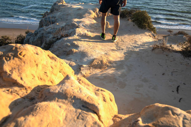 um homem de tênis de gradiente amarelo e preto. parado na beira de um penhasco, no fundo do mar. - high calorie - fotografias e filmes do acervo