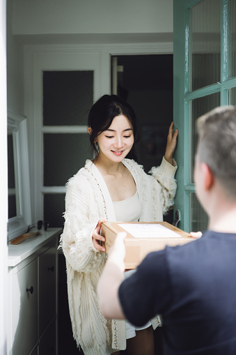 Asian beautiful woman receiving her package from the delivery man.