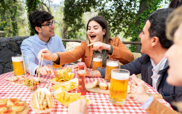 istock Group of mixed age friends drinking beer pints at pub out side while eating tapas- Happy people having fun together in farmhouse garden 1428476845