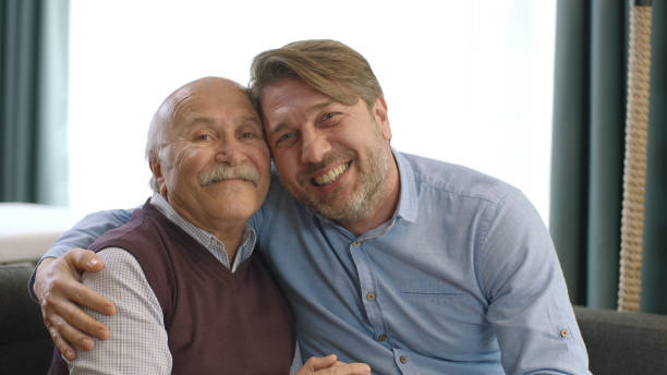 The young man is visiting his elderly father on a special day. A young man visits his father during Eid Mubarak (Turkish Ramadan or Şeker Bayram). Muslim holiday traditions concept. The old man and his child are laughing at the camera. father allah stock pictures, royalty-free photos & images