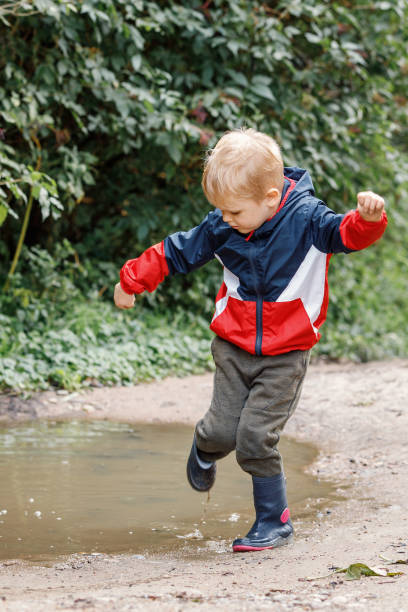 istock Little boy splashing in a mud puddle, jumping into a puddle 1428478406