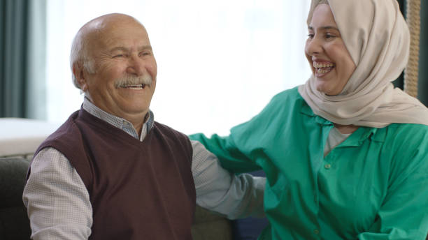 Young hijab woman visiting her elderly father on a special day. Smiling happy young woman in hijab visiting her elderly father. Adult daughter in hijab hugging father celebrates Eid or Father's Day. father allah stock pictures, royalty-free photos & images