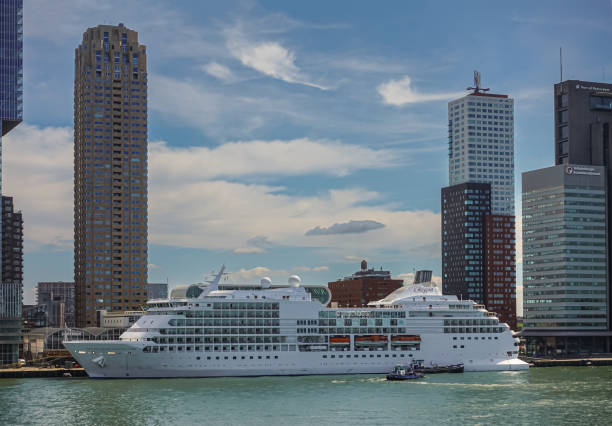 Rotterdam, Netherlands - July 11, 2022: White Seven Seas Navigator cruise ship docked at terminal on Kop van Zuid dock under blue cloudscape with high rise buildings in back