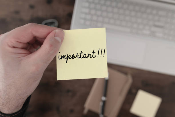 istock top down view of hand holding yellow sticky note with word IMPORTANT 1428491875