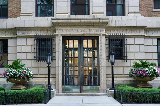 Front door of elegant apartment building with large flower pots