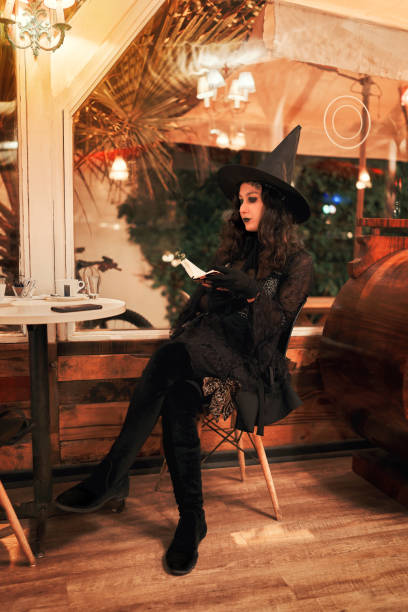 istock latin woman dressed as a witch sitting in a cafe reading a book 1428505069