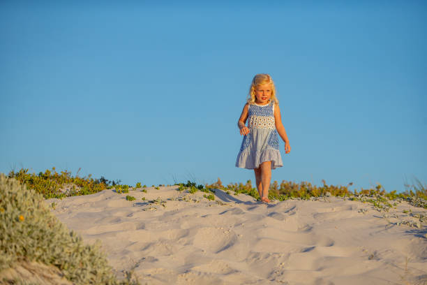 istock Little girl walking on sand dunes 1428508817
