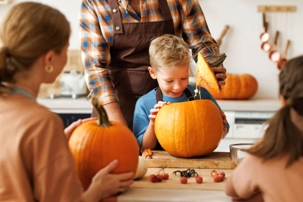 istock Happy boy smiling  while helping dad carve Halloween pumpkin. 1428513940