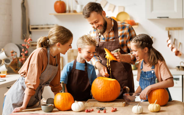 istock Son and dad making Jack-o-Lantern together at home, carving Halloween pumpkin 1428513992